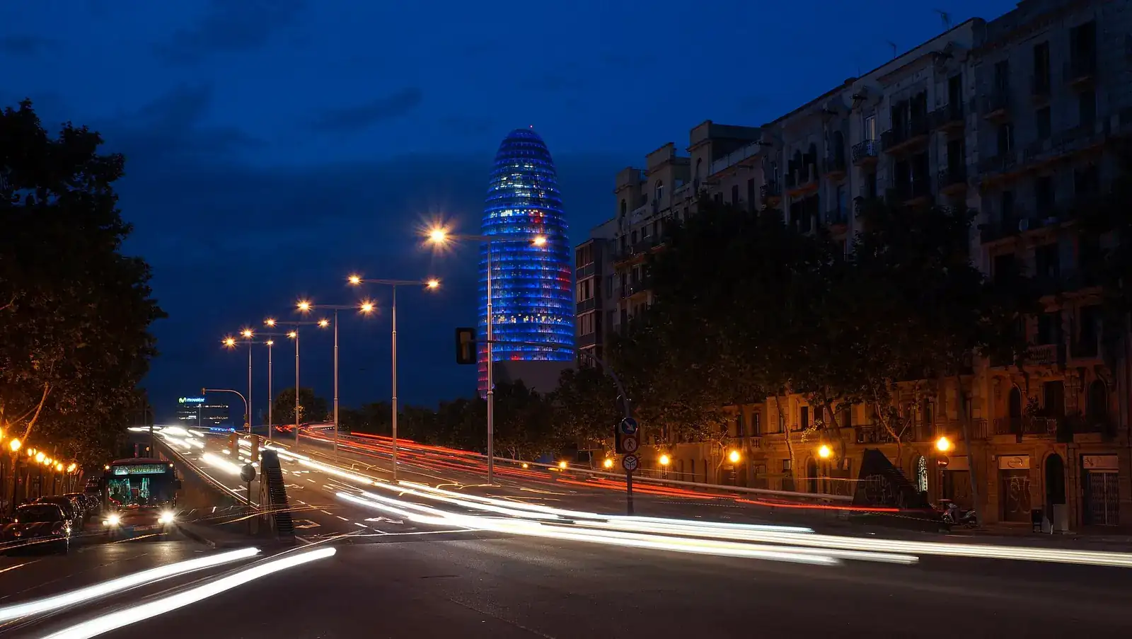 Trànsit nocturn en una avinguda de Barcelona amb la Torre Glòries al fons